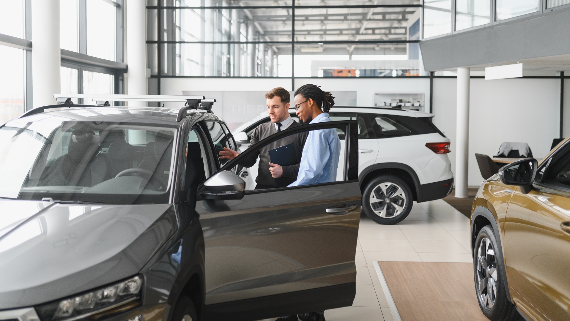 A consultant at a car dealership helps a customer choose a new car